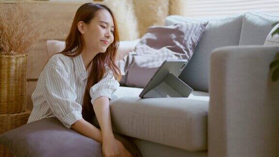 亚洲美女穿着休闲布家居隔离隔离在客厅家居室内的沙发上享受在平板电脑上看网络电影