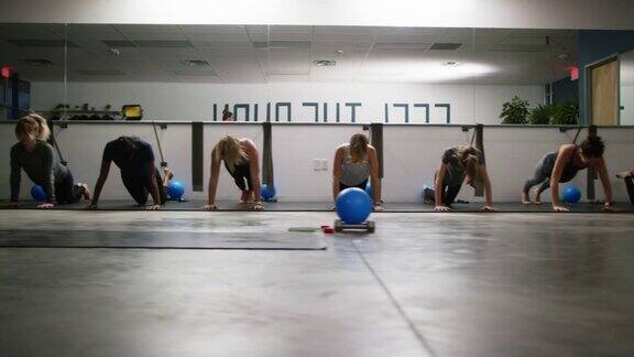 一群20多岁的女性在健身房的地板上练习俯卧撑