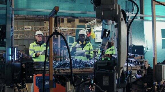 一组从事防护工作的技术工程师控制和指导工厂工业机器人机械臂的维护