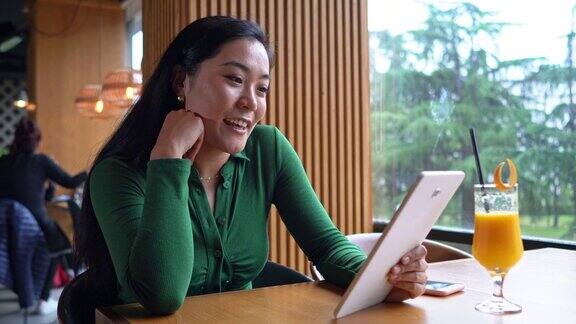亚裔现代女性自由职业者在她的数码平板电脑上进行视频通话时也挥手致意