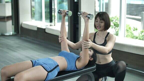 女健身教练在健身房举杠铃进行胸肌训练作为体育锻炼