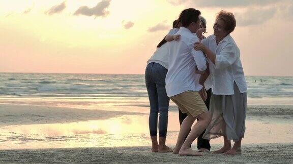 剪影快乐的亚洲大家庭拥抱日落在沙滩上的海浪家庭生活方式人人寿保险多代人老人假期关系孩子假期退休健康保健理念