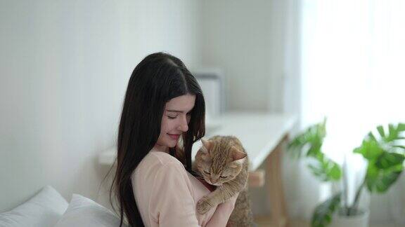 美丽的女人在假期的空闲时间和她可爱的猫在家里玩