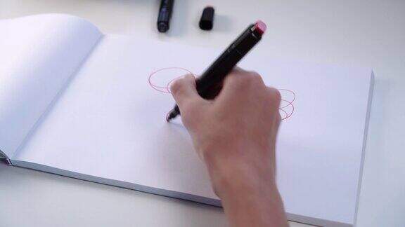 一个少年的手用毡尖笔在一本相册的白纸上画画