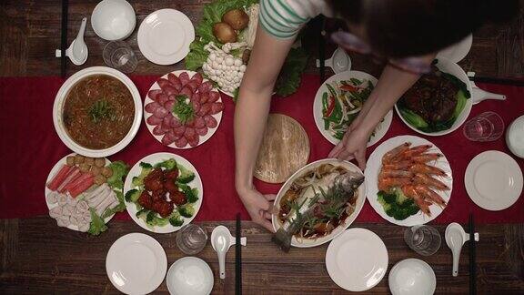 俯视图人们的手把美味的农历新年的菜肴放在餐桌上红色的桌布和餐具