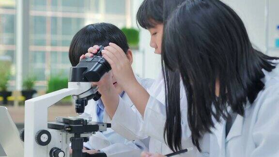 教师和学生在实验室利用显微镜进行科学实验