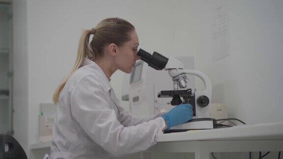 穿着制服的女医生在实验室办公室用显微镜进行分析在实验室工作的科学家在现代医学实验室工作的微生物学家