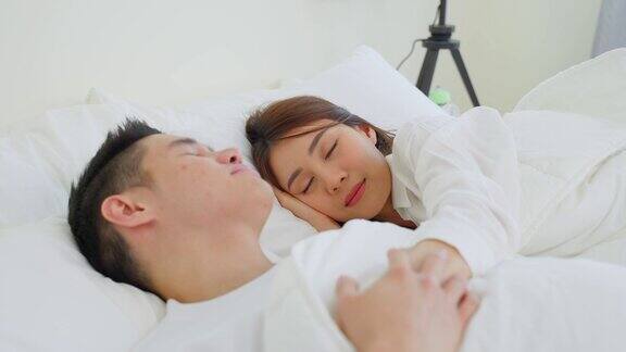 亚洲有吸引力的年轻夫妇躺在床上睡觉在卧室美丽的新婚夫妇穿着睡衣的男人和女人清晨在房子里一起躺在舒适的枕头上感到幸福和放松