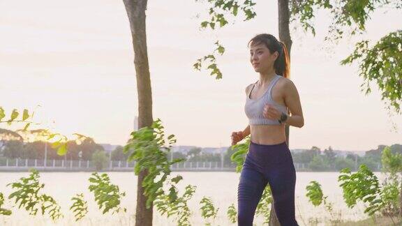 亚洲年轻美丽的女人为健康在傍晚日落在街道上的公园运动员健康和坚定的女孩锻炼通过慢跑锻炼户外运动为她的健康