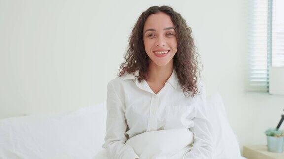 拉丁美人的肖像穿着睡衣微笑看着相机有魅力的年轻女性感到新鲜和快乐从床上早起在家里早上的卧室健康的生活方式