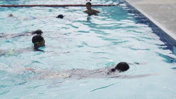 亚洲的中国游泳运动员在游泳教练的指导下在泳池边练习游泳