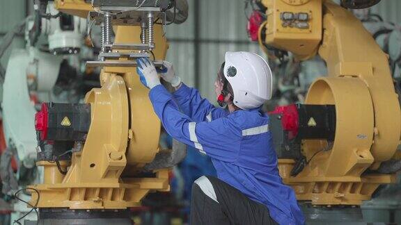 亚洲女工程师穿着安全制服在机械臂工厂从事自动化生产根据维护计划检查系统和更换零件或在制造工厂测试操作
