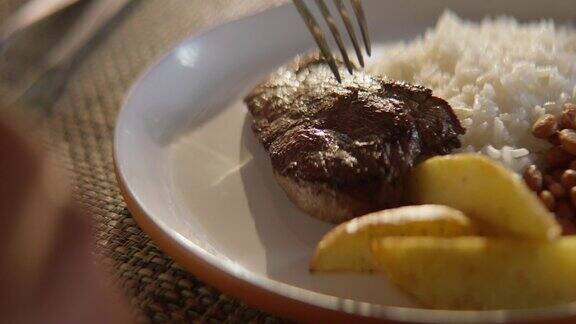 一盘米饭豆子土豆和牛排的特写把牛排放在盘子里