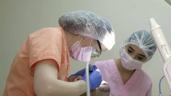 一个女牙医在附近治疗一个病人