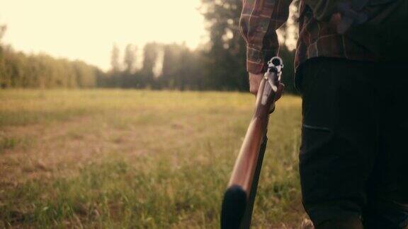一个猎人拿着猎枪在草原上行走的后视图(慢镜头)