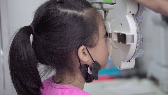 一个亚洲小女孩在诊所里用光镜检查眼睛