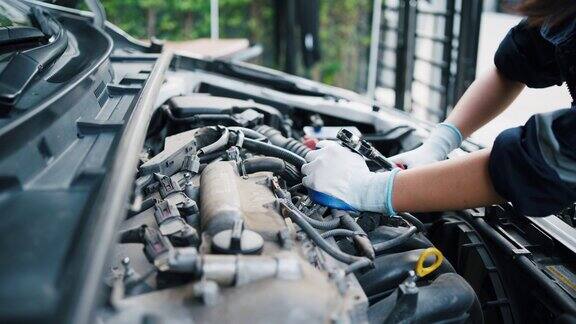 女汽车修理工用套筒扳手在车库里修理发动机