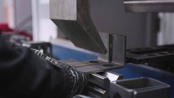 一个特写镜头显示了一个工人的手在一个专门的机器上弯曲钢零件这个车间专门从事金属加工