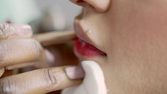一名化妆师用唇线小心翼翼地在模特的嘴唇上涂上口红