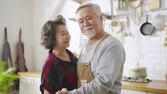 亚洲成熟的老年夫妇在家里的厨房里跳舞和微笑