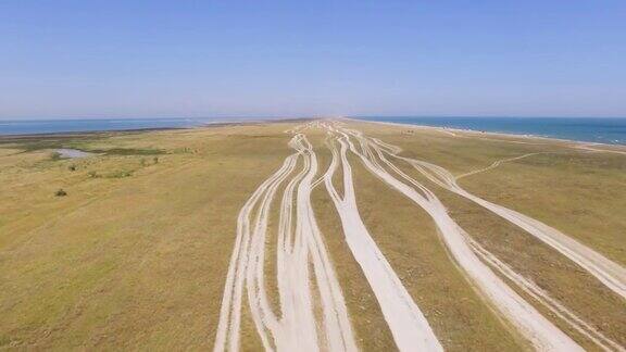 航拍图:蓝色海洋附近盐碱地的乡村道路