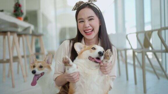亚洲女性狗柯基咖啡馆员工穿着制服照顾抱抱小狗在狗咖啡馆室内背景微笑和愉快