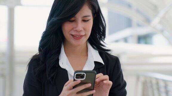 微笑的亚洲商务女性在商业区上班时使用手机商务人士与同事聊天商务官员的生活方式