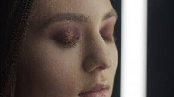 化妆的步骤化妆师用化妆刷在女孩的眼睛上涂上深色眼影