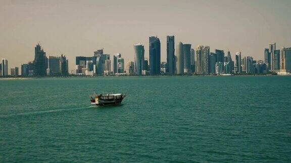 中东卡塔尔多哈一艘传统渔船在摩天大楼附近经过
