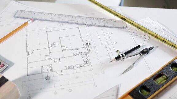 办公室桌子上的房屋平面图蓝图纸和维修工具