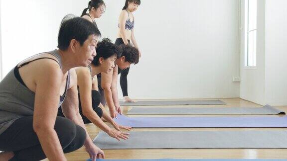 退休老年妇女推出瑜伽垫锻炼身体在健身房做瑜伽