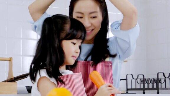 亚洲家庭的母亲和女儿一起随着音乐跳舞在家里的厨房里享受煮早餐健康保健的日常活动理念