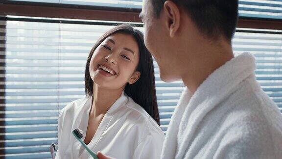 幸福的亚洲夫妇在浴室用牙刷刷牙