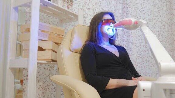 牙齿美白紫外线一个女人坐在牙医的椅子上牙釉质美白灯美丽的微笑牙齿的健康4k