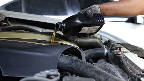 汽车机械师在保养维修服务站更换并给发动机注入新机油机械师在修理厂给汽车注入机油给汽车换油时正在倒新油