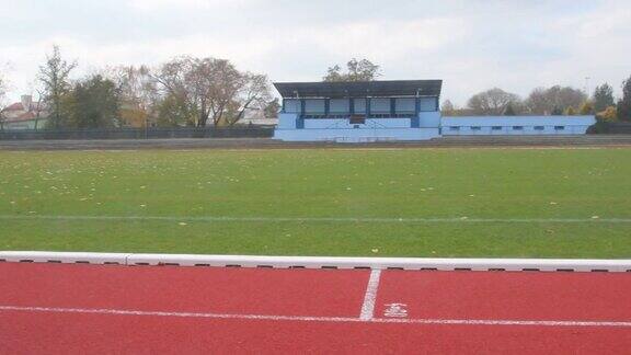 红色的跑道在体育馆的秋天秋天废弃的田径跑道足球场的全景完成田径和足球赛季