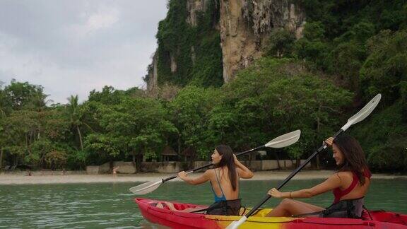 年轻的亚洲女性朋友们在暑假里一起在海里划皮艇