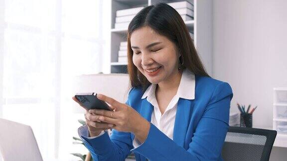 女性企业家女商人成功的亚洲女商人使用智能手机手机应用程序在线交流坐在办公室的桌子在室内
