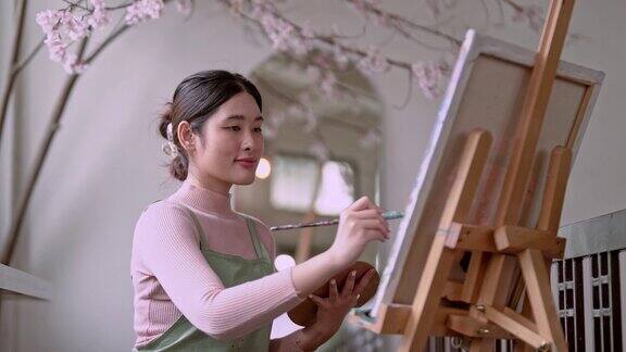 亚洲女艺术家在她的艺术工作室里用画笔在画布上作画和使用不同的丙烯酸颜料艺术家的创作理念
