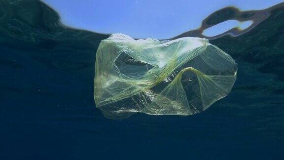 塑料污染黄色塑料袋在bubuwater慢镜头丢弃的塑料袋在阳光下的蓝色水面下慢慢漂流欧洲地中海漂浮着黄色塑料袋