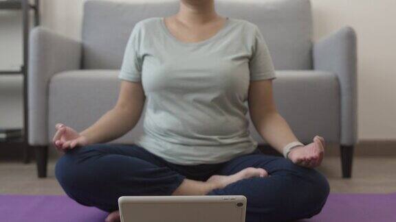 年轻女子在家的客厅里练习莲花体式瑜伽周末进行冥想呼吸练习