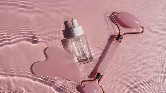 化妆品瓶与移液管在粉红色的背景与水滴纯净水有阳光和阴影的反射缓慢运动的波浪水某保湿护肤品的广告