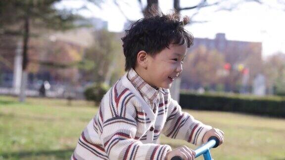 一个小男孩在公园里骑自行车