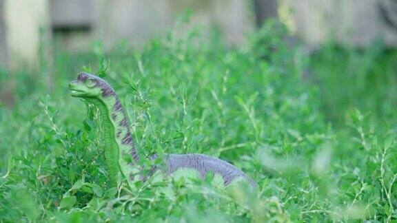 一只塑料恐龙正在绿色的草地上行走古老的动物有选择性的重点