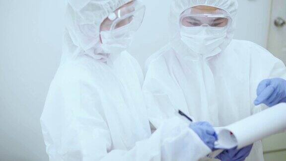 冠状病毒大流行期间两名身穿防护服的医务人员在剪贴板上讨论检测结果