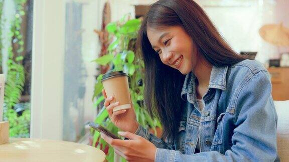 年轻的亚洲美女使用智能手机在咖啡厅咖啡厅打字写短信在手机上网上购物转账支付网上银行