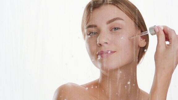 年轻女子用水滴滴在玻璃后的脸颊上