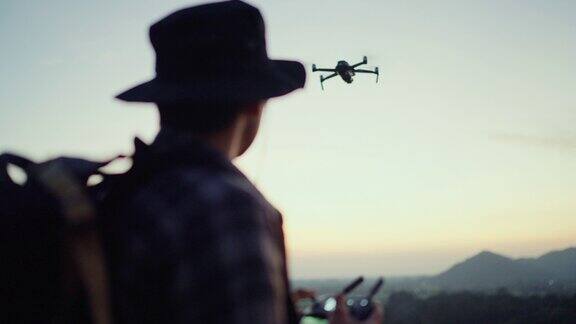 早上在山景上亚洲游客使用无人机的剪影