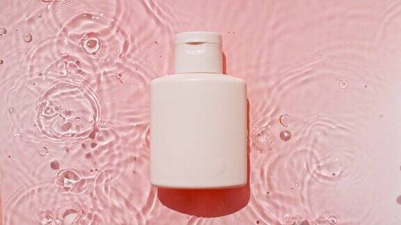 化妆品面霜一瓶乳液精华液胶束爽肤水和乳液在粉红色的水背景与飞溅美容spa医学皮肤护理化妆品的广告