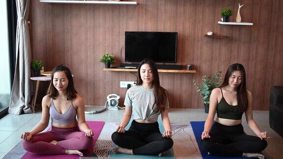 一群亚裔中国女性朋友在家庭客厅里一起练瑜伽